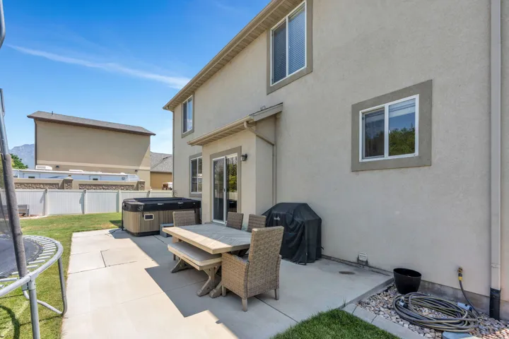 Rear exterior featuring a concrete patio, sliding glass door access, and a spa