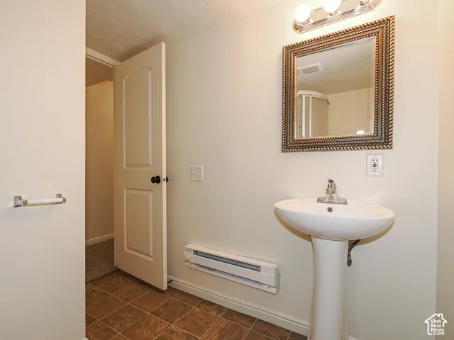 Pedestal sink with chrome faucet, framed vanity mirror, and three-light fixture