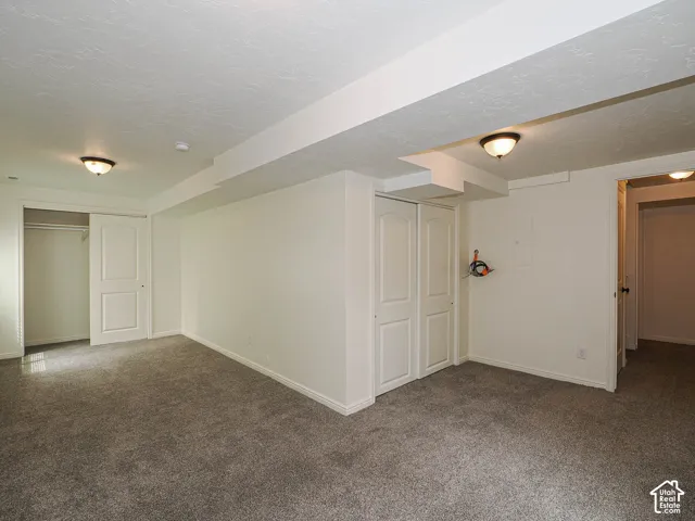 Carpeted room featuring two flush-mount light fixtures, white walls, and built-in closet storage with bi-fold doors