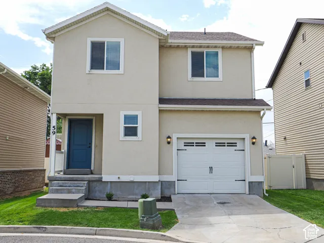 Two-story stucco exterior with a gable roof, concrete steps leading to a blue entry door, an attached garage with carriage-style doors, and concrete driveway