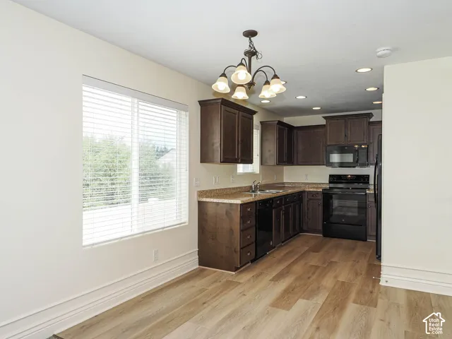 Kitchen featuring dark wood-finish cabinetry, black appliances, a double basin sink, and wood-finish flooring