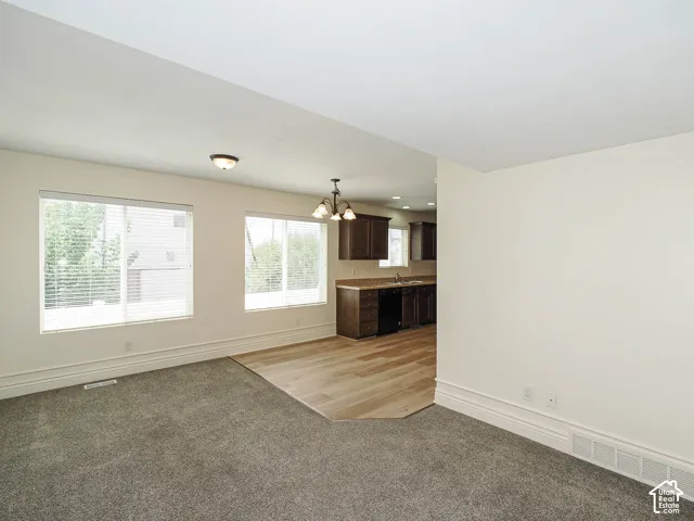 Plush carpeting in living area, wood-finish flooring in dining area, dark wood cabinetry, window blinds, and recessed lighting