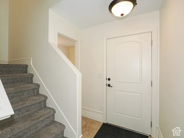 Welcoming foyer featuring a white six-panel entry door with sidelights, neutral wall finishes, and a curved staircase with gray carpeted treads and white painted railings
