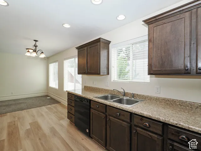 Wood-finish flooring with dark wood cabinetry, a double basin sink, and recessed lighting