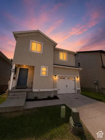 Two-story residence featuring a neutral stucco exterior, an attached single-car garage, and a covered front entry with a blue door