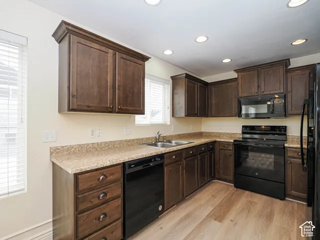Kitchen featuring wood-finish cabinetry, granite-style countertops, stainless steel dual basin sink, and recessed lighting