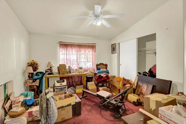 Interior room featuring a white ceiling fan with integrated lighting, a window with natural light, and a sliding door closet with wire shelving