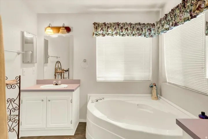 Corner garden tub featuring white paneling and a built-in shelf