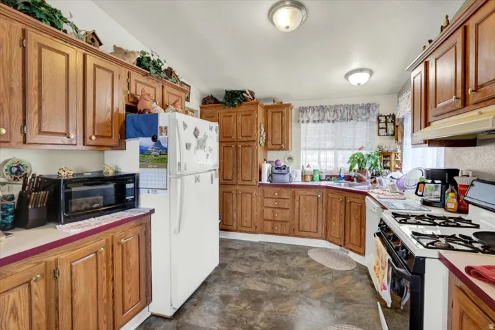 Kitchen featuring extensive wood-finish cabinetry, white countertops with a maroon edge, and a double-basin stainless steel sink