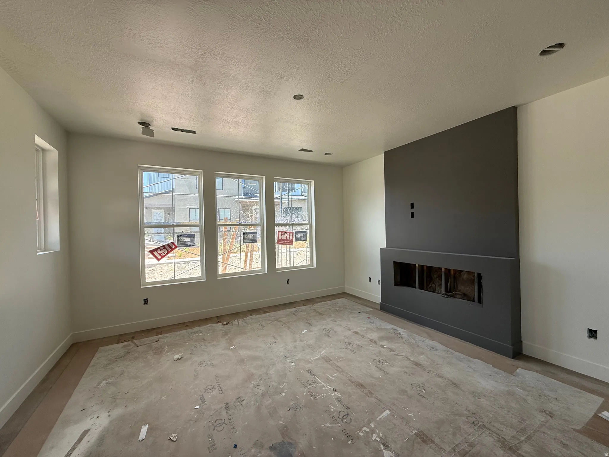 Living area featuring a modern dark-toned fireplace surround, multiple large windows, recessed ceiling lighting, a track light fixture, and light-toned wall finishes