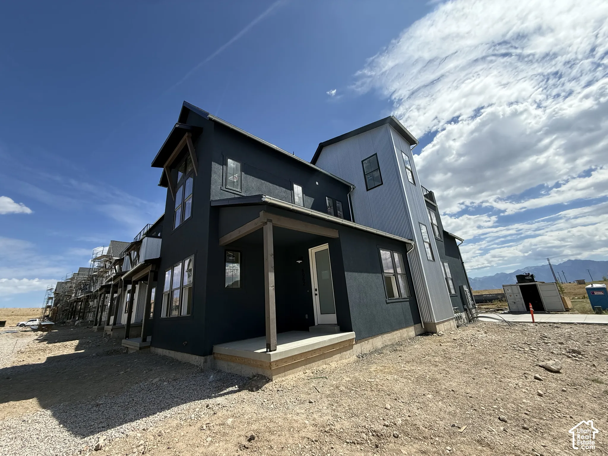 Multi-level exterior with dark stucco and light-colored siding