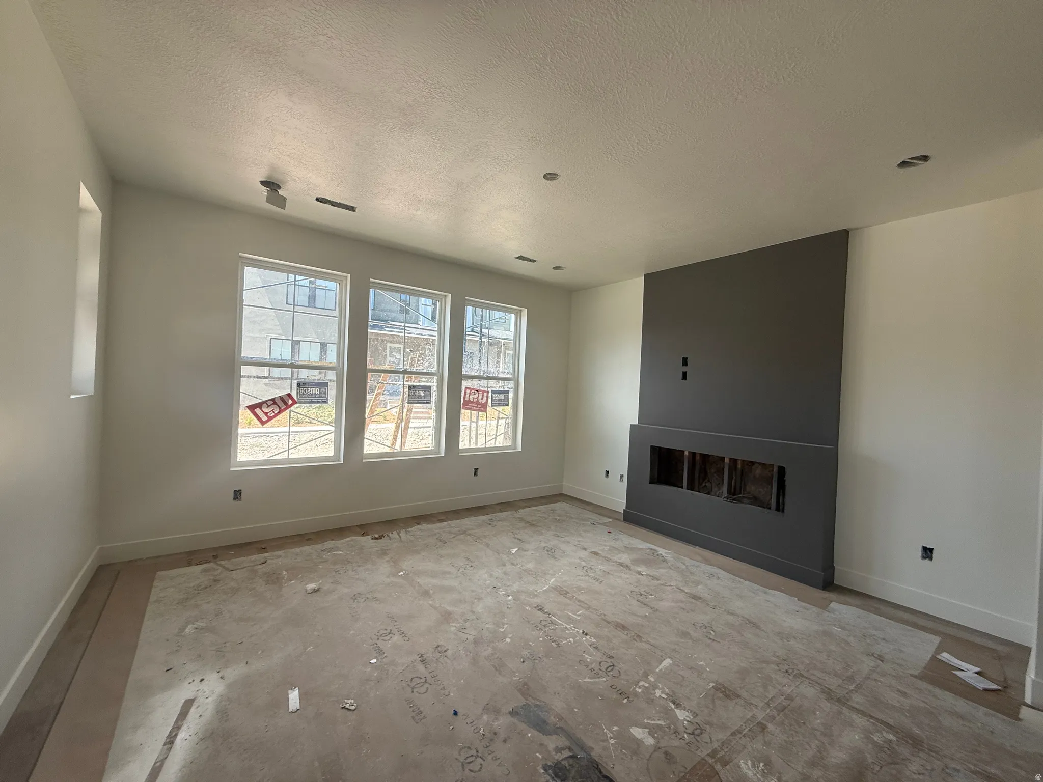 Spacious room featuring a contemporary fireplace with a dark accent wall, recessed lighting, and multiple large windows