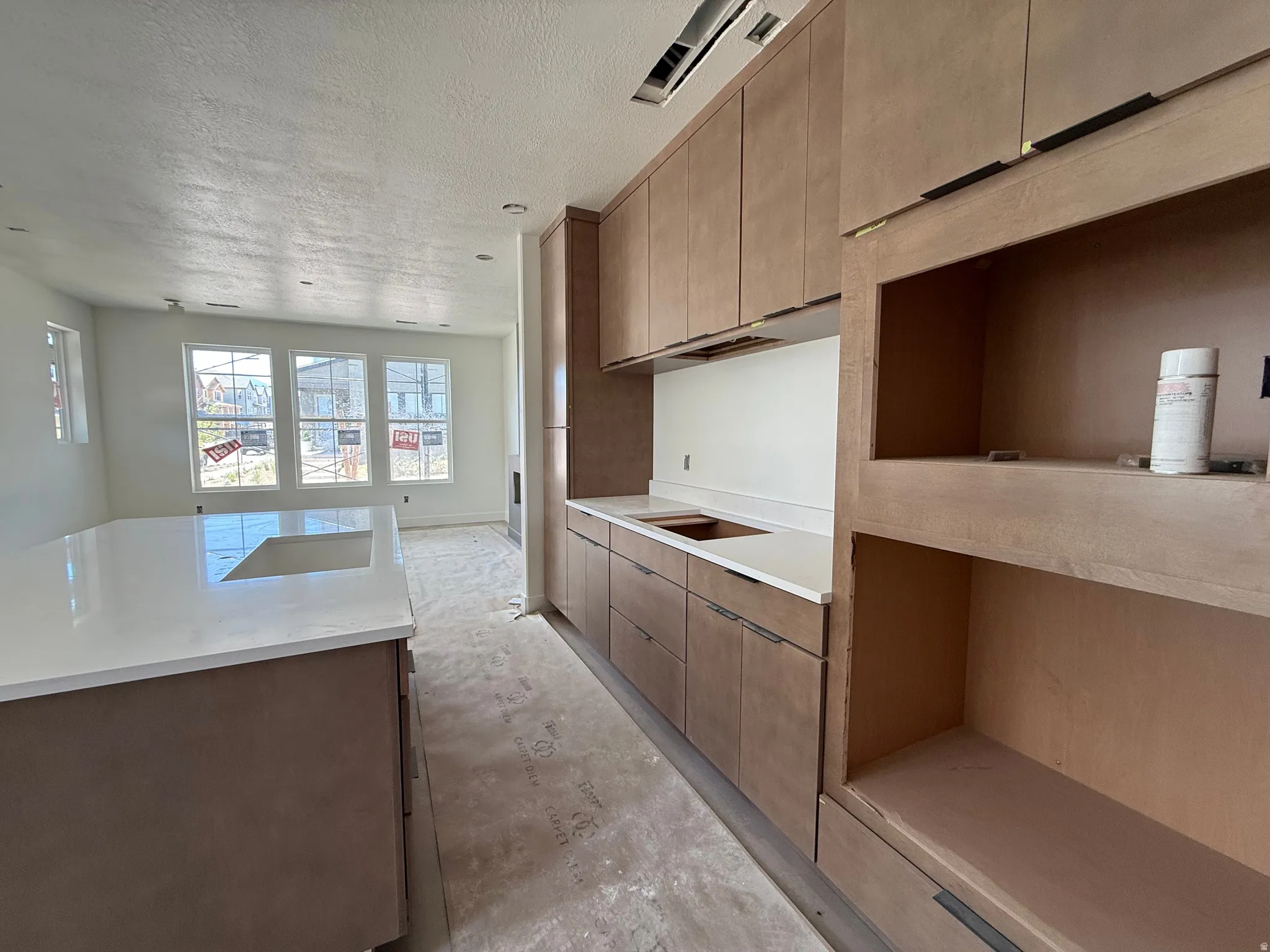 Contemporary kitchen featuring light wood-finish cabinetry, white countertops, and an integrated kitchen island