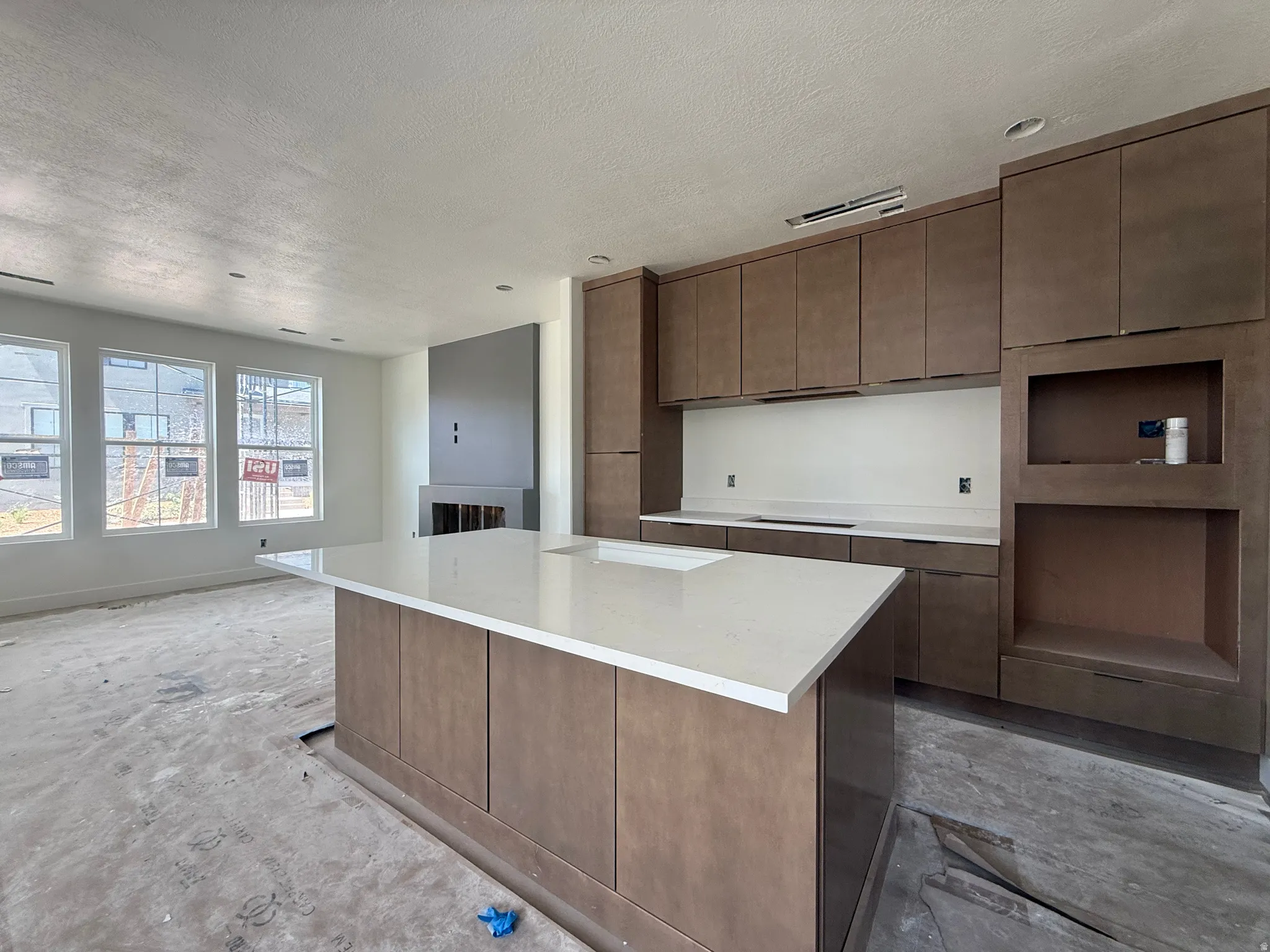 Expansive kitchen island featuring a range hood, range cooktop, built-in oven and microwave.