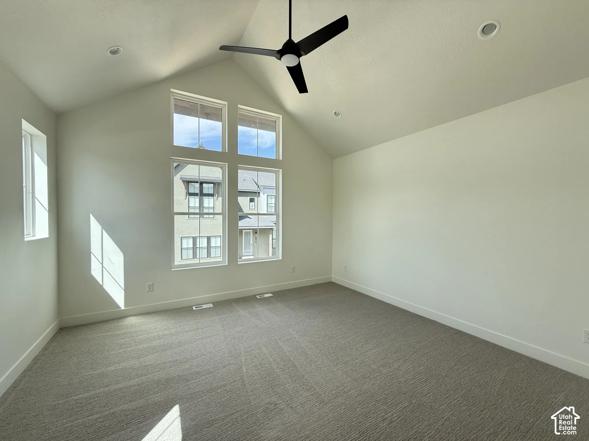 Vaulted ceiling with a ceiling fan, recessed lighting, expansive windows, light-toned carpeting, and neutral wall finishes