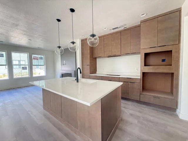 Spacious kitchen featuring an island with a white countertop, modern cabinetry, and recessed lighting