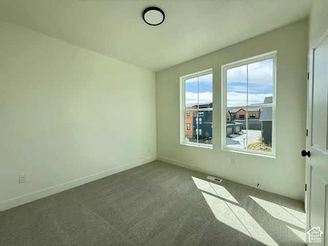 Neutral-toned carpeting, white painted walls, and a flat ceiling