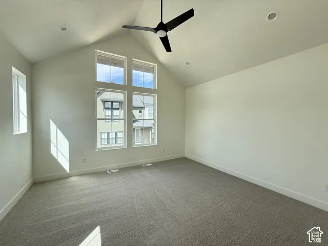 Vaulted ceiling with a ceiling fan, recessed lighting, expansive windows, light-toned carpeting, and neutral wall finishes