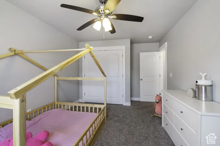 Carpeted room featuring a ceiling fan with integrated lighting, a white six-drawer dresser with silver hardware, and white interior doors with matching hardware