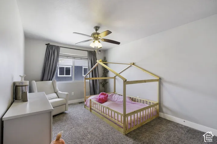 Carpeted room featuring a ceiling fan with integrated lighting, a window with dark gray curtains, and light gray wall paint