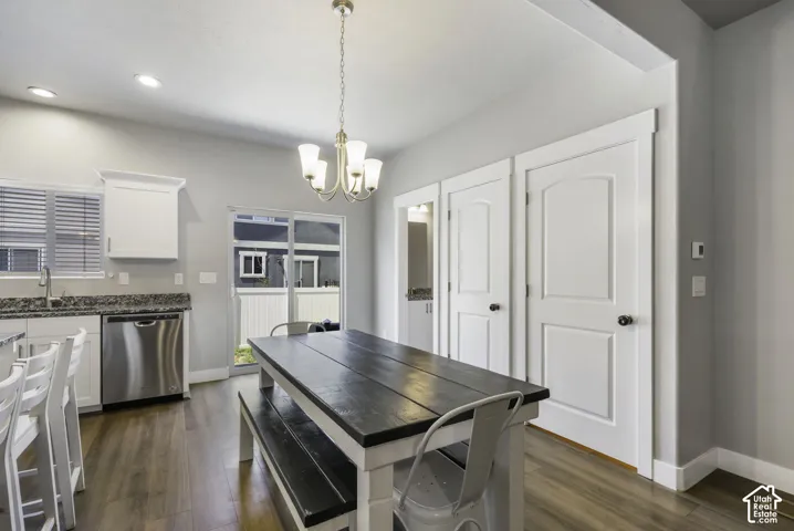 Kitchen and dining area featuring wood-finish flooring, white cabinetry, stainless steel dishwasher, speckled countertops, and a sliding glass door