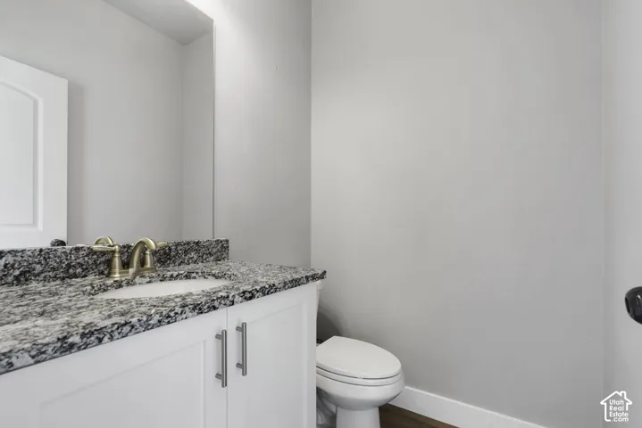 Half Bathroom vanity with a granite countertop, undermount sink, and brushed brass faucet