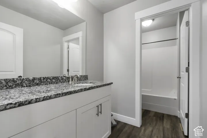 Bathroom featuring a spacious vanity with a speckled countertop, a single basin sink with a chrome faucet, and white cabinetry