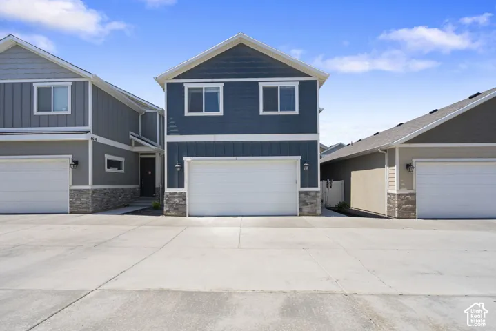 Two-story exterior featuring blue horizontal siding, white trim, stone veneer accents, and an attached two-car garage