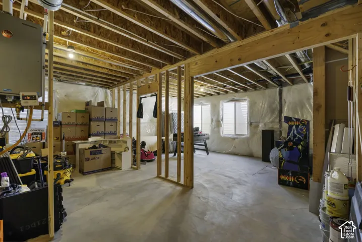 Unfinished basement with exposed wood framing, concrete flooring, and multiple windows