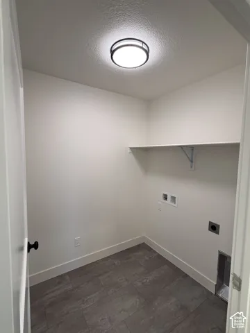 Utility room featuring gray tile flooring, a wall-mounted shelf, and a flush-mount ceiling light fixture