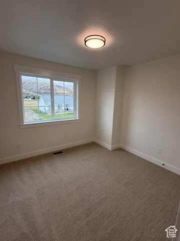 Neutral-toned wall-to-wall carpeting, window with a mountain backdrop, sliding sash window with a decorative grille, and a flush-mount circular ceiling light fixture
