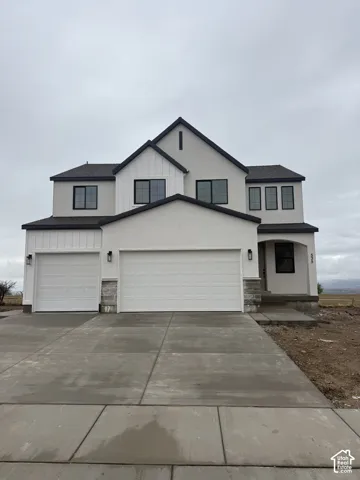 Multi-level exterior featuring a stucco and board-and-batten facade, stone masonry accents, a three-car garage, and dark-framed windows