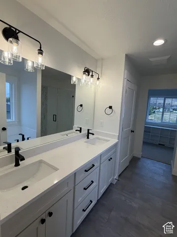 Double vanity featuring white cabinetry, quartz countertops, undermount sinks, matte black hardware, and industrial-style glass light fixtures