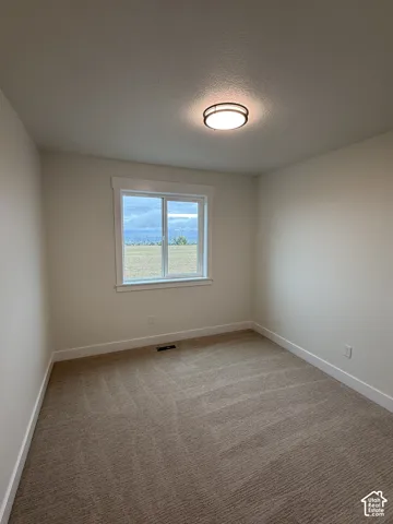 Neutral-toned carpeting, crisp wall finishes, window with mountain backdrop, and circular flush-mount ceiling lighting