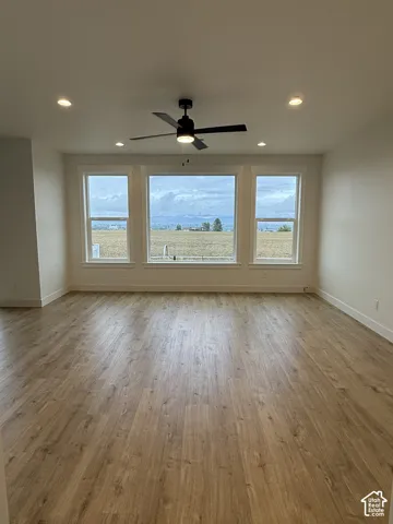 Interior space featuring wood-finish flooring, a matte black ceiling fan, recessed lighting, and a triple-window configuration with a mountain backdrop