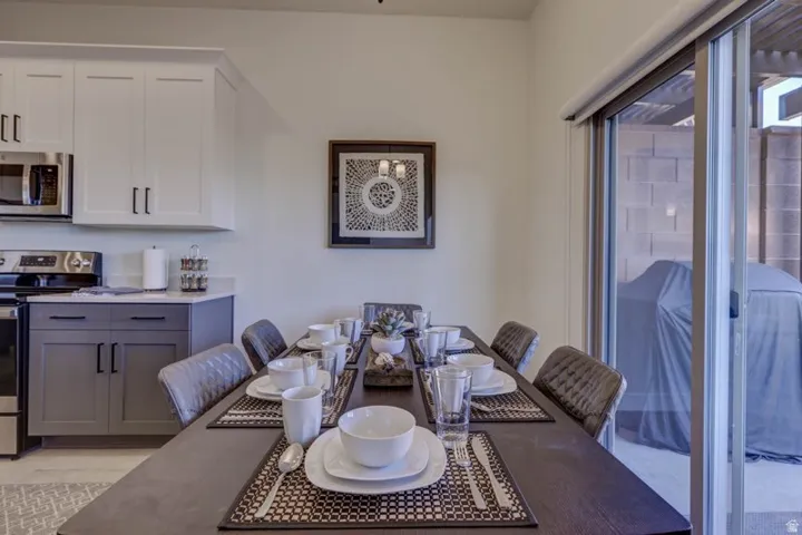 Dining area featuring a dark wood-finish table, upholstered chairs, and direct patio access through a sliding glass door