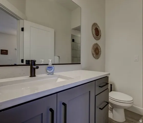 Bathroom vanity featuring a light-toned countertop with an integrated sink, dark bronze-finish faucet, and gray cabinetry with modern black hardware