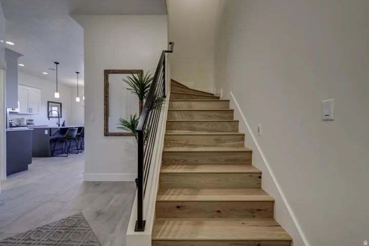 Light wood-finish staircase with black metal balusters and white risers