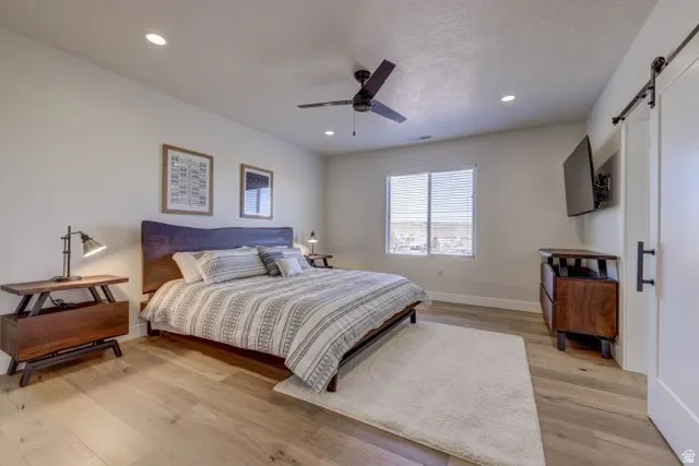 Spacious room featuring light wood-finish flooring, recessed lighting, and a dark ceiling fan