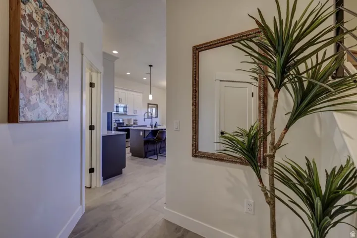 Hallway entrance featuring light grey flooring, a white wall, and a staircase with open risers and metal railings