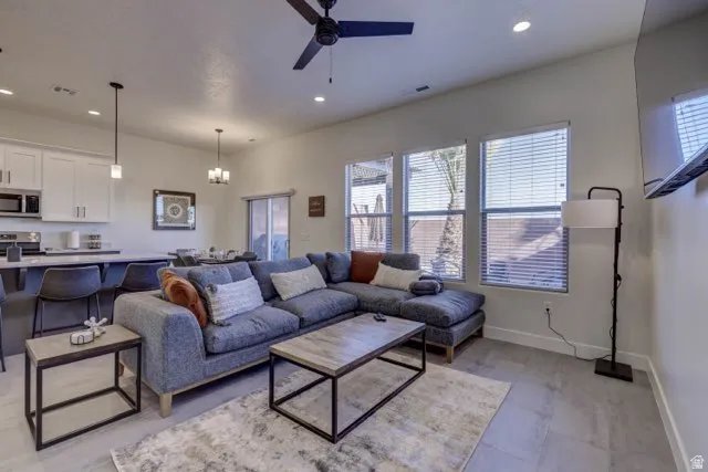 Open-concept living space featuring wood-finish flooring, recessed lighting, a ceiling fan, and multiple windows with blinds