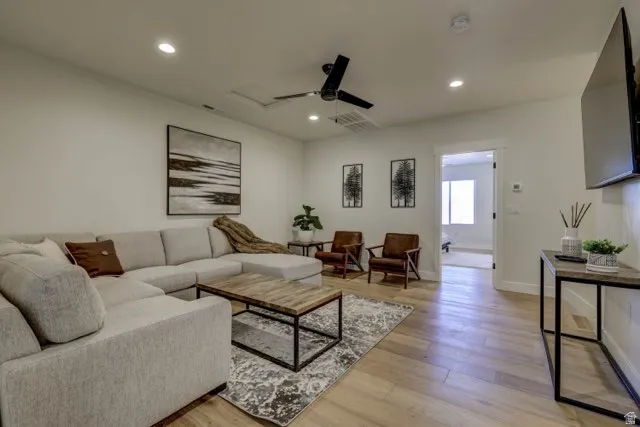 Open-concept living space with wood-finish flooring, recessed lighting, and a ceiling fan