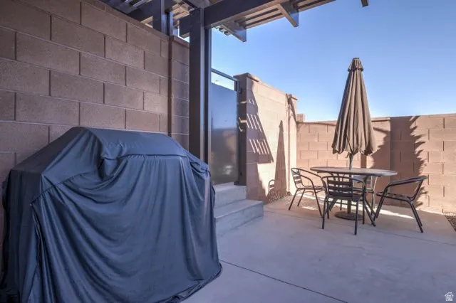 Concrete patio with privacy block walls and a metal gate