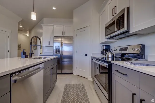 Modern kitchen with stainless steel appliances, including a microwave, range, dishwasher, and refrigerator