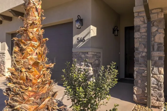 Stucco exterior featuring stone accents, a dark garage door, and a prominent front entry with a dark door