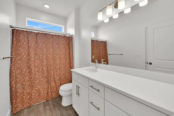 Bathroom featuring a long single-sink vanity with white cabinetry, a light-toned countertop, and brushed nickel hardware