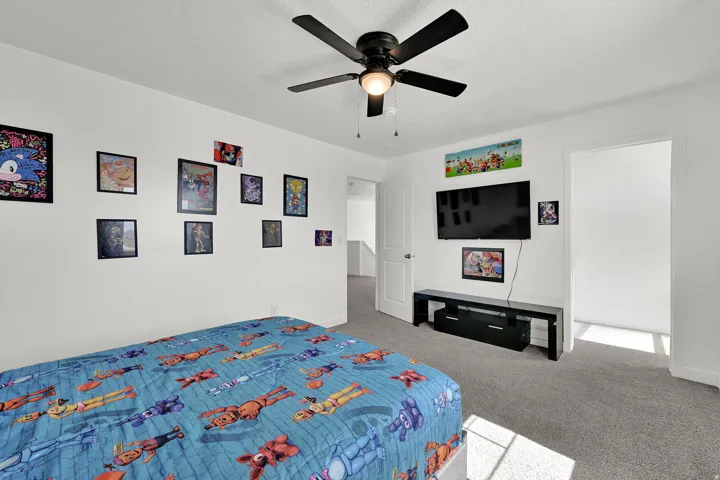Spacious and bright bedroom with ceiling fan and neutral flooring.