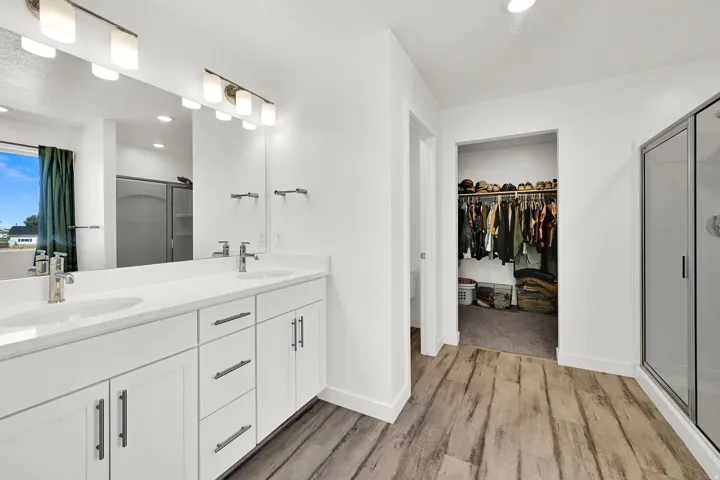 Double vanity with white cabinetry and chrome hardware, white stone countertops