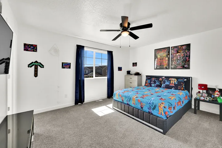 Spacious and bright bedroom with ceiling fan and neutral flooring.