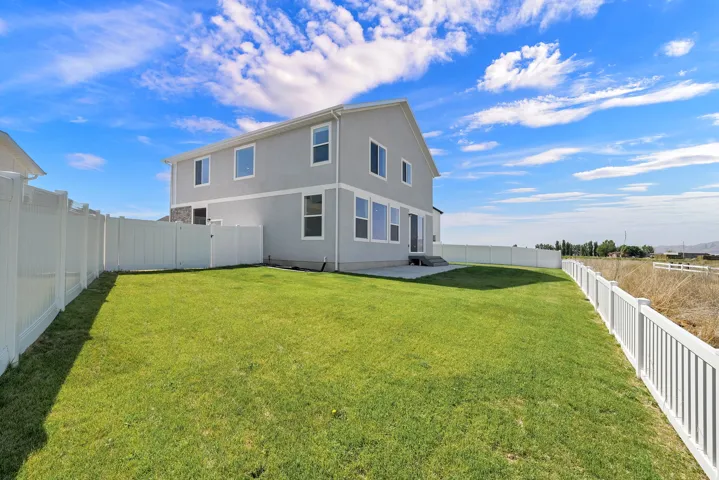Expansive backyard with a manicured lawn, full vinyl fencing, and a concrete patio